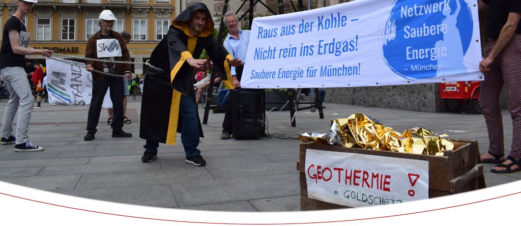Das Münchner Kindl mit einem Banner "Haus aus der Kohle, Nicht rein ins Erdgas!" und der Geothermie als "goldenen Schatz"