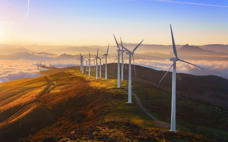 Man sieht Windräder auf einer Anhöhe stehen