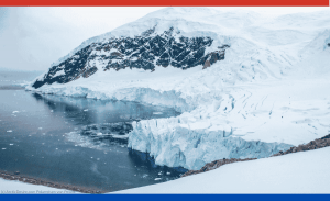 Man sieht ein Bild aus der Antarktis: Ein schneebedeckter Berg, der mit viel Eis ins Meer ragt.